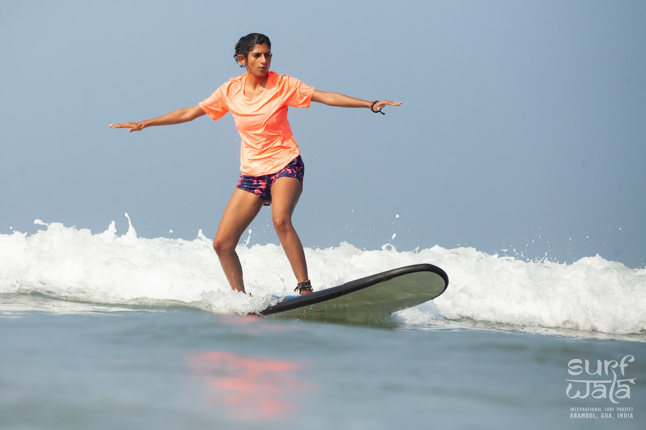 Surfer Girl surfing on a wave for beginners on Arambol beach in Goa India